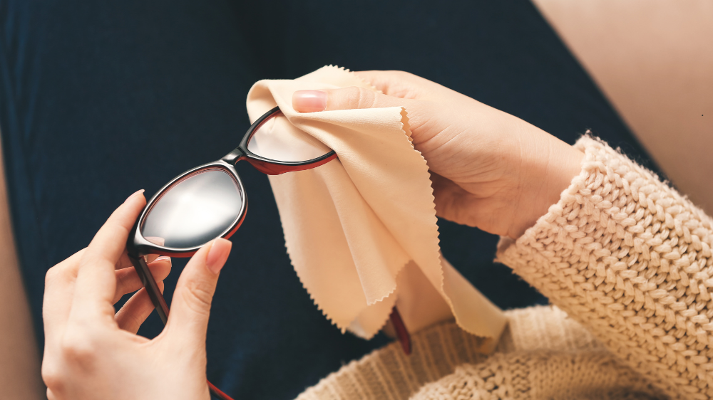 A person is cleaning their glasses with a cloth.