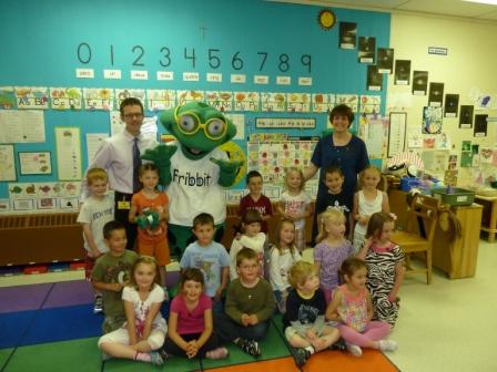 A group of children are posing for a picture with a fribler mascot