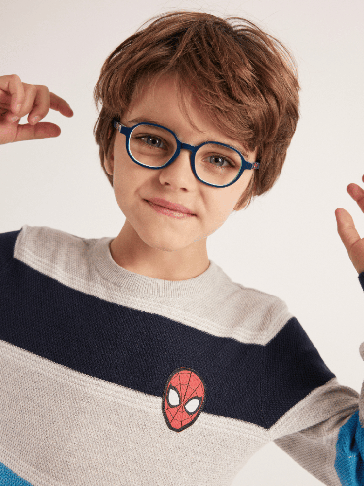 A young boy wearing glasses and a spiderman sweater