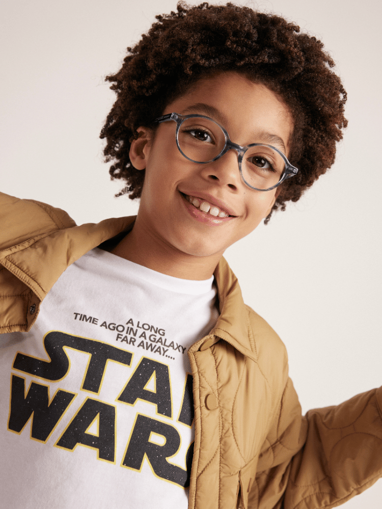 A young boy wearing glasses and a star wars t-shirt.