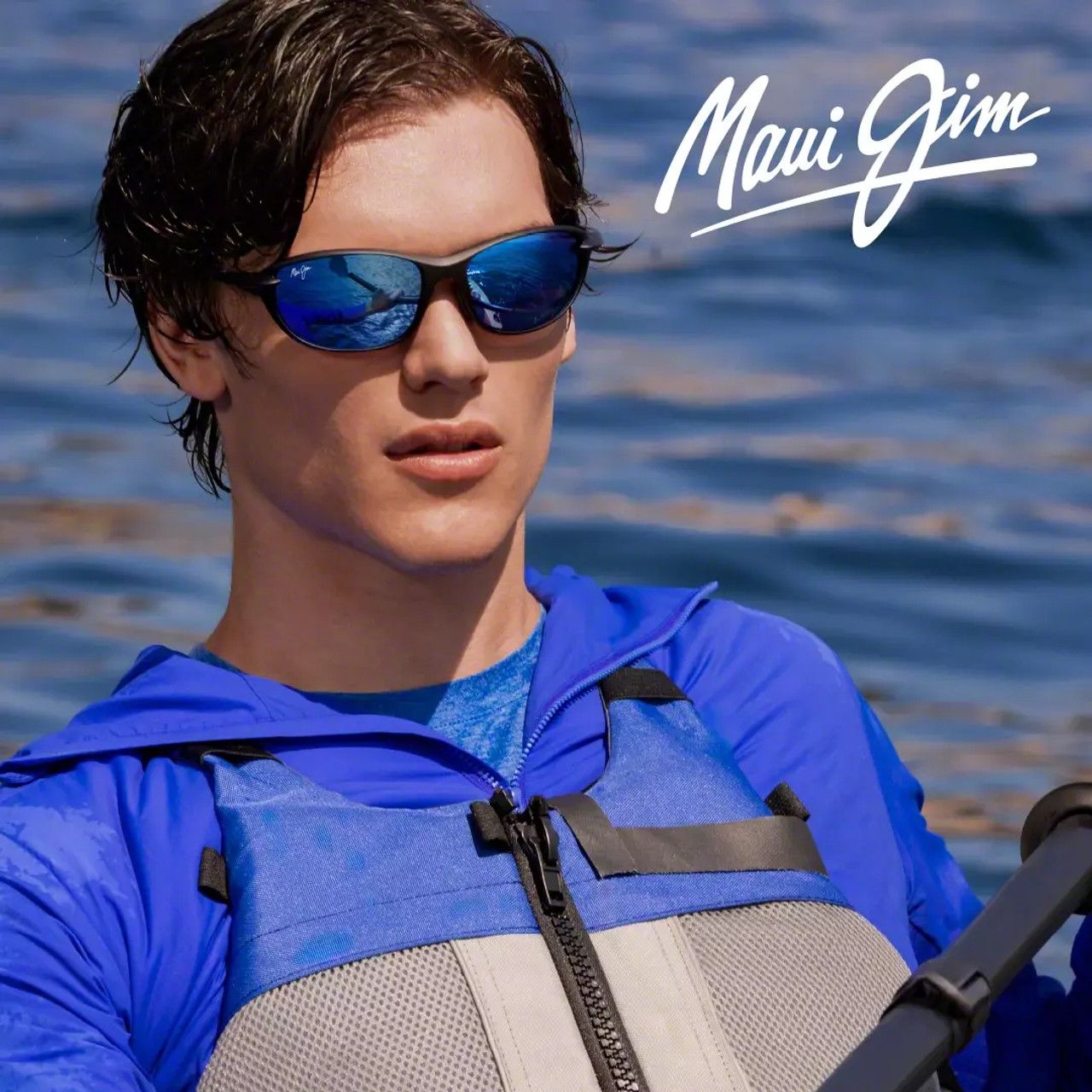 Man wearing blue life vest and sunglasses on a boat with Maui Jim logo over water