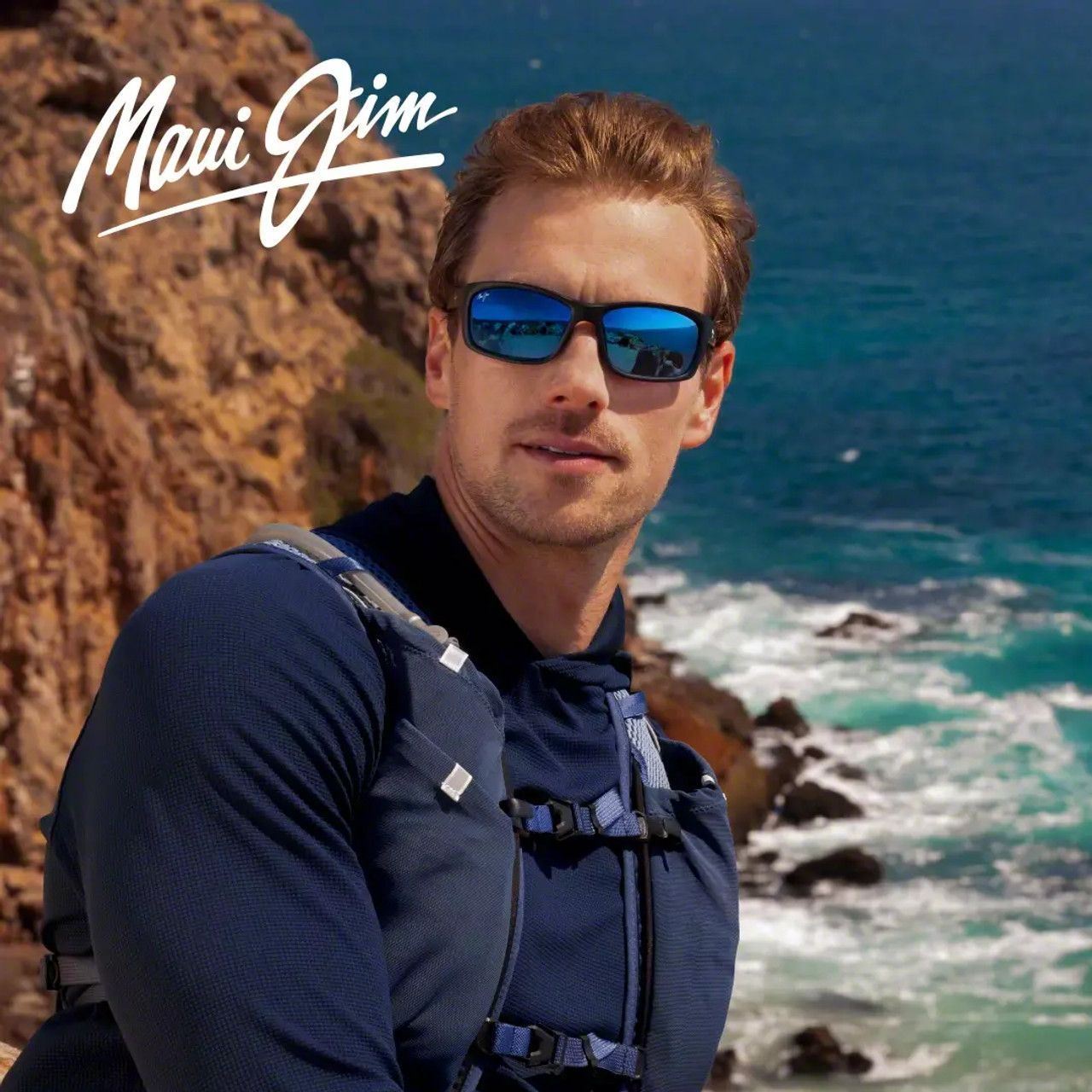 Man wearing blue sunglasses and hiking gear on a rocky Maui coastline with ocean waves