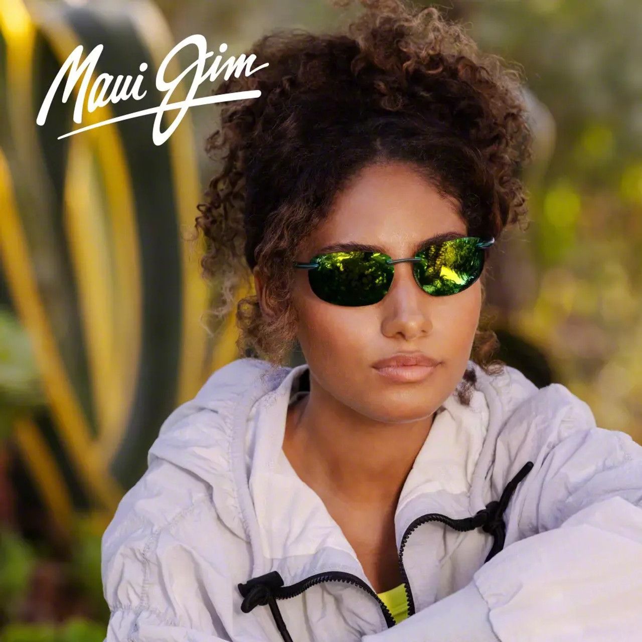 Person in reflective sunglasses and white jacket against a blurred yellow-green outdoor background.