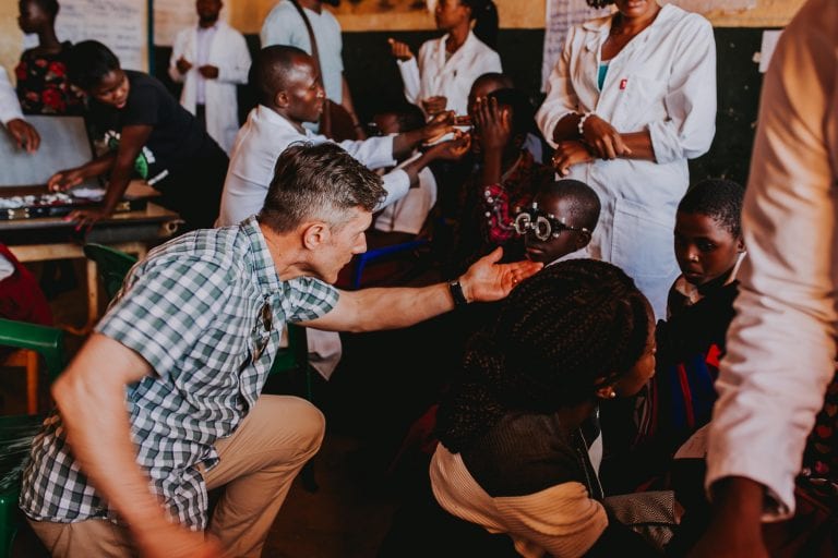 A man is kneeling down in front of a group of people.