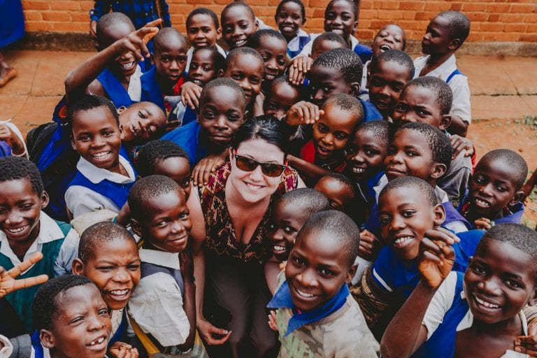 A woman is posing for a picture with a group of children.