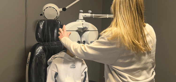Person adjusting a white and black chair in an eye exam room