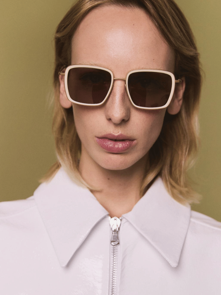 A woman wearing sunglasses and a white shirt
