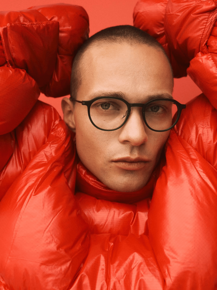 The man is wearing glasses and a red jacket.