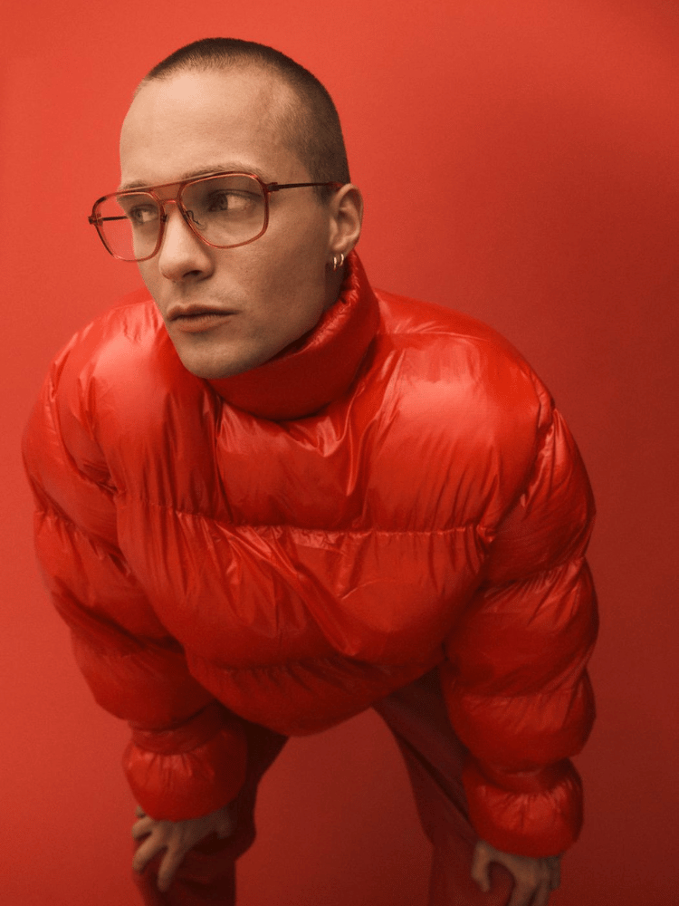 The man is wearing glasses and a red jacket.
