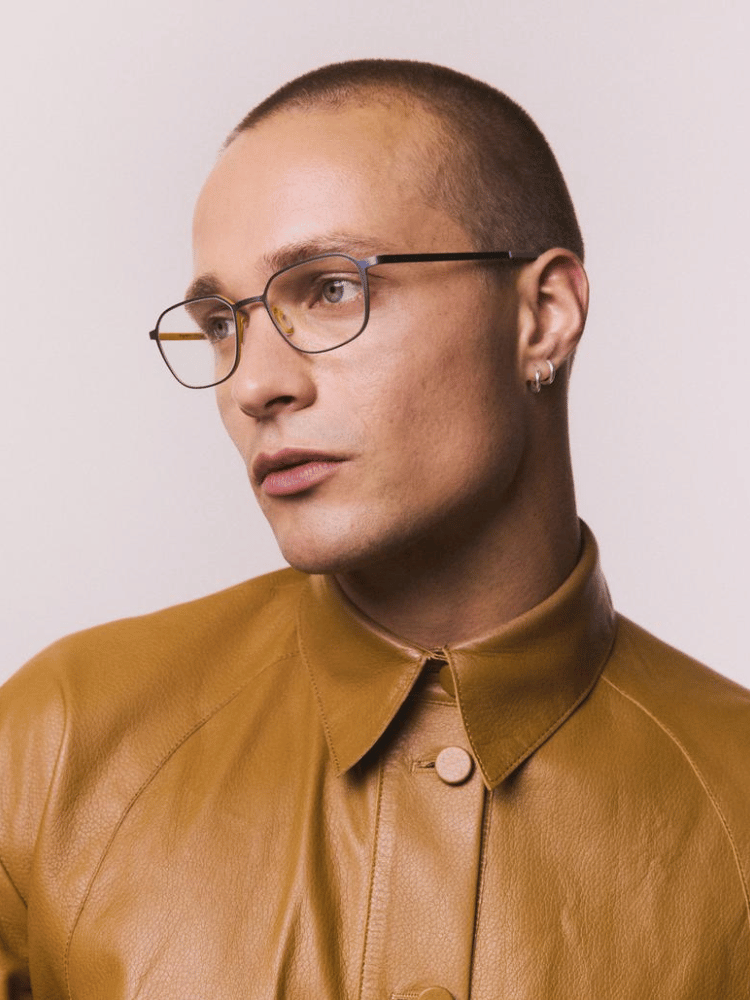 A man wearing glasses and a brown leather jacket.