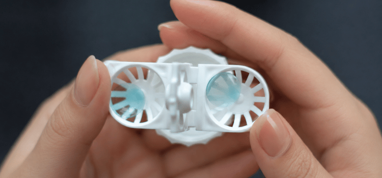 Hands holding a small white plastic device with two circular openings