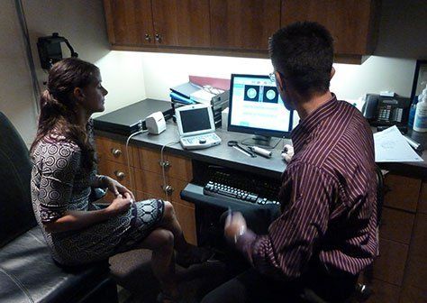 A man and a woman are sitting in front of a computer