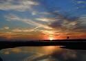 A sunset over a body of water with a bridge in the foreground.