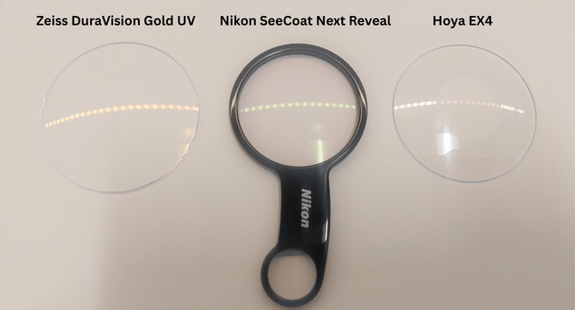 Three eyeglass lenses: Zeiss DuraVision Gold UV, Nikon SeeCoat Next Reveal, and Hoya EX4, with a magnifying glass.