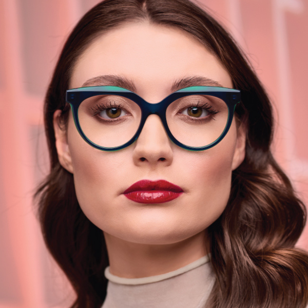 A woman wearing glasses and red lipstick is looking at the camera.