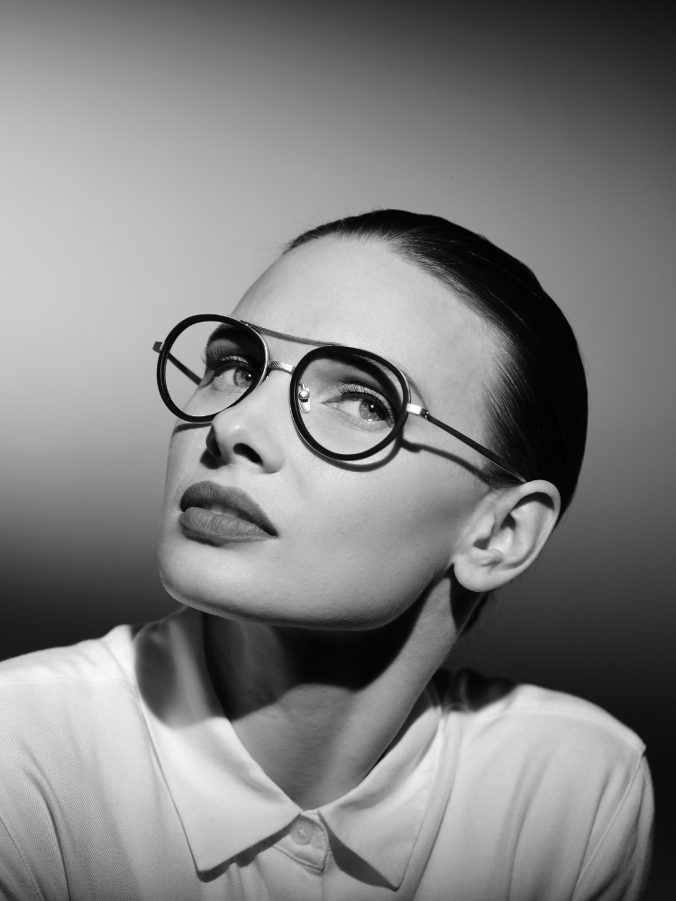 A woman wearing glasses and a white shirt is looking up.
