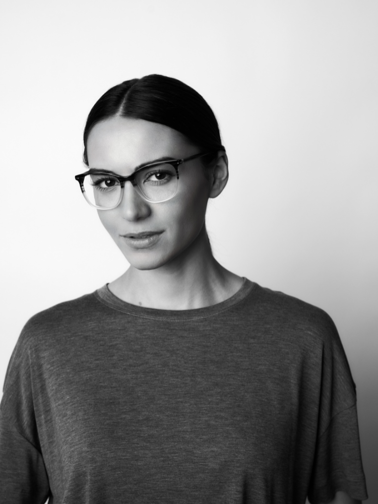 A black and white photo of a woman wearing glasses and a gray shirt.