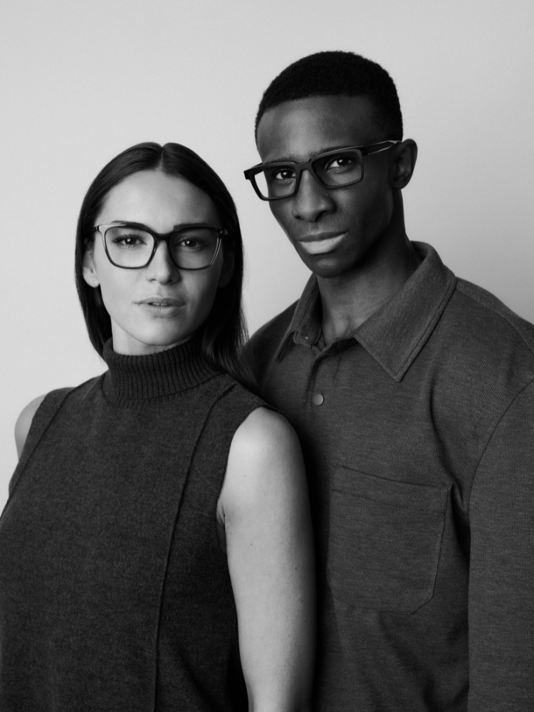 A man and a woman wearing glasses are posing for a black and white photo.