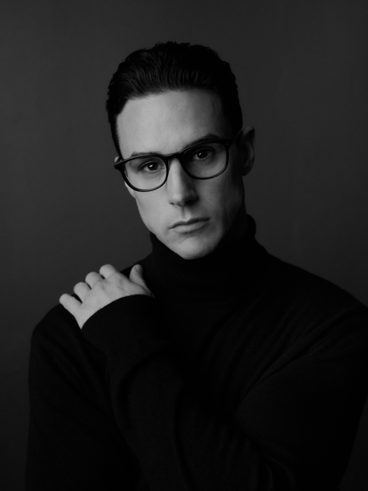 A black and white photo of a man wearing glasses and a turtleneck.