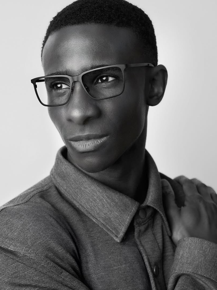 A black and white photo of a man wearing glasses and a shirt.