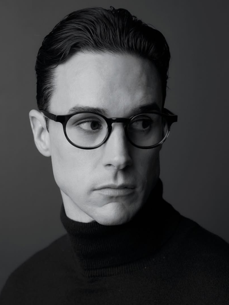A black and white photo of a man wearing glasses and a turtleneck.