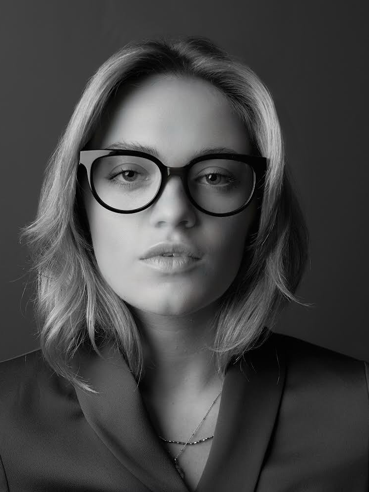 A black and white photo of a woman wearing glasses.