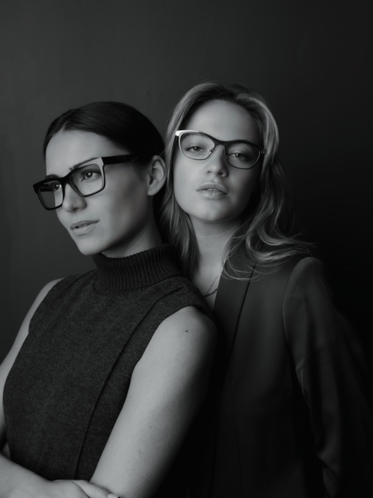 Two women wearing glasses are posing for a black and white photo.
