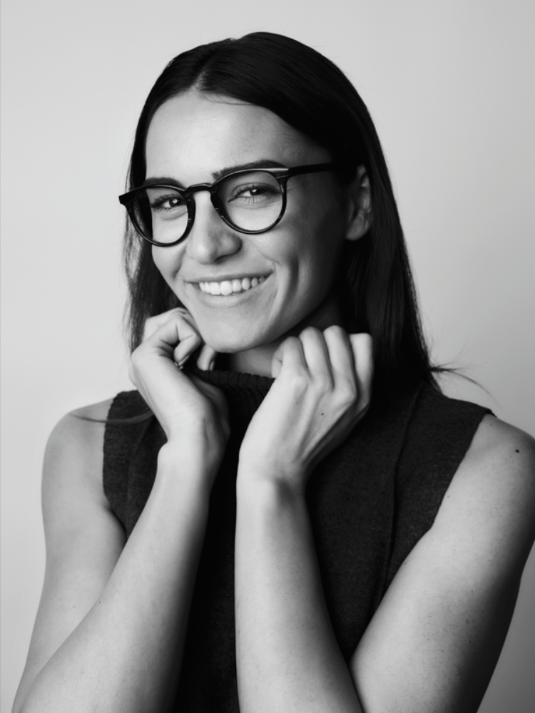 A woman wearing glasses is smiling in a black and white photo
