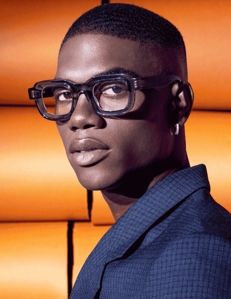 A close up of a man wearing glasses and a blue jacket.