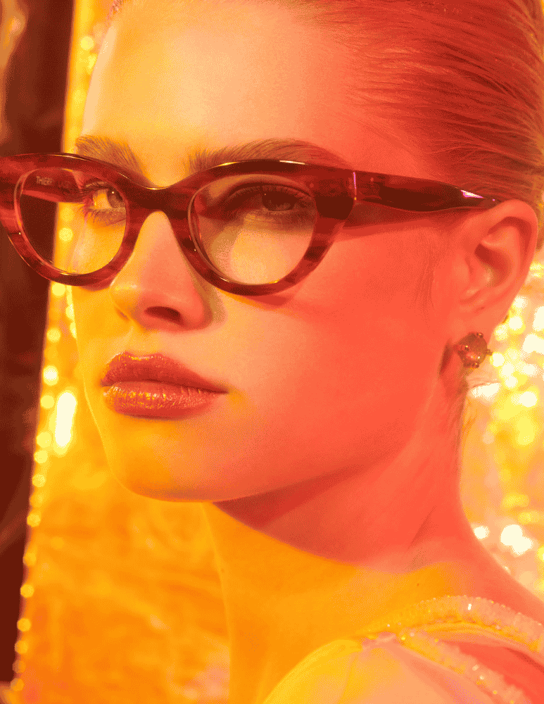 A close up of a woman wearing glasses and earrings.