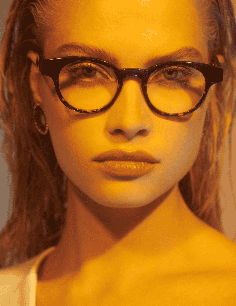 A close up of a woman wearing glasses and earrings.