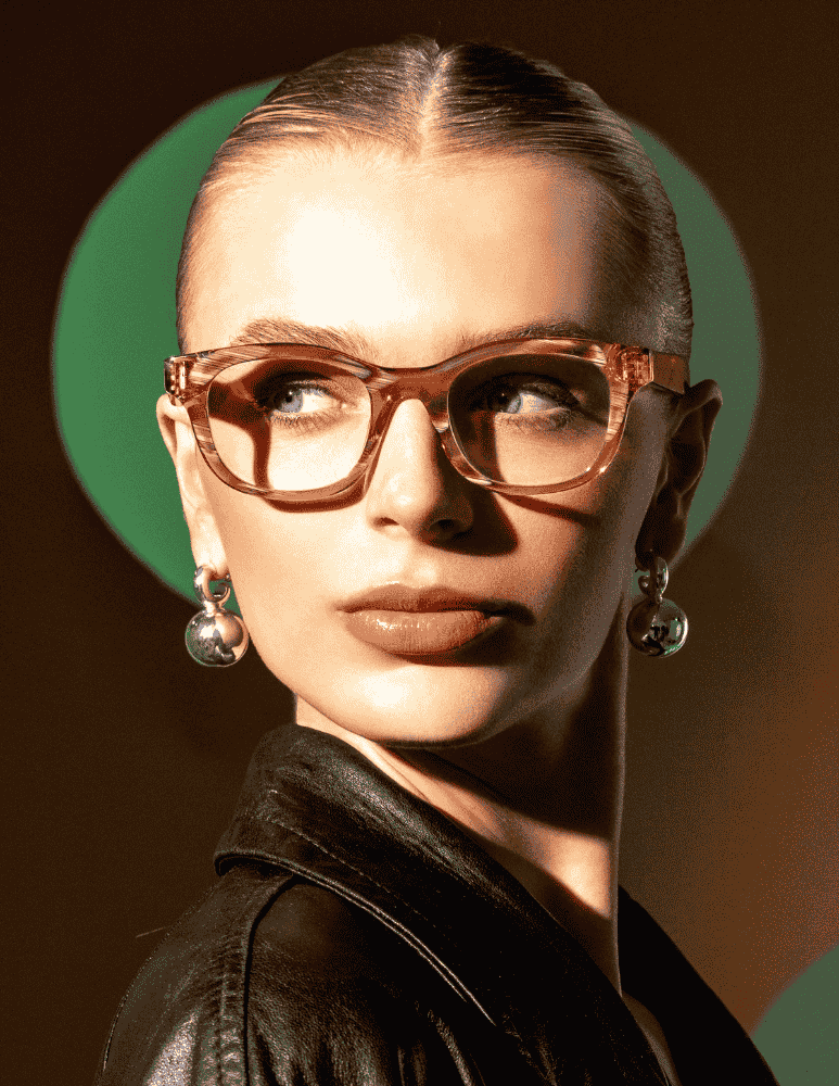 A woman wearing glasses and earrings is standing in front of a green circle.