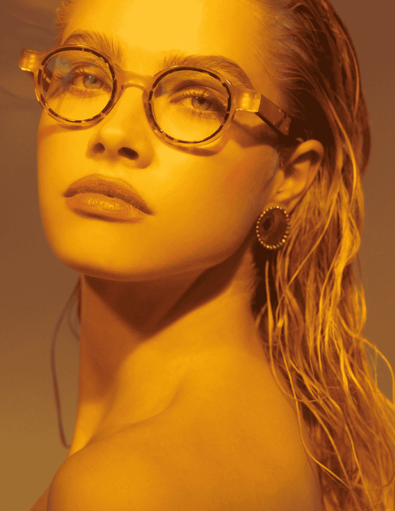A close up of a woman wearing glasses and earrings.