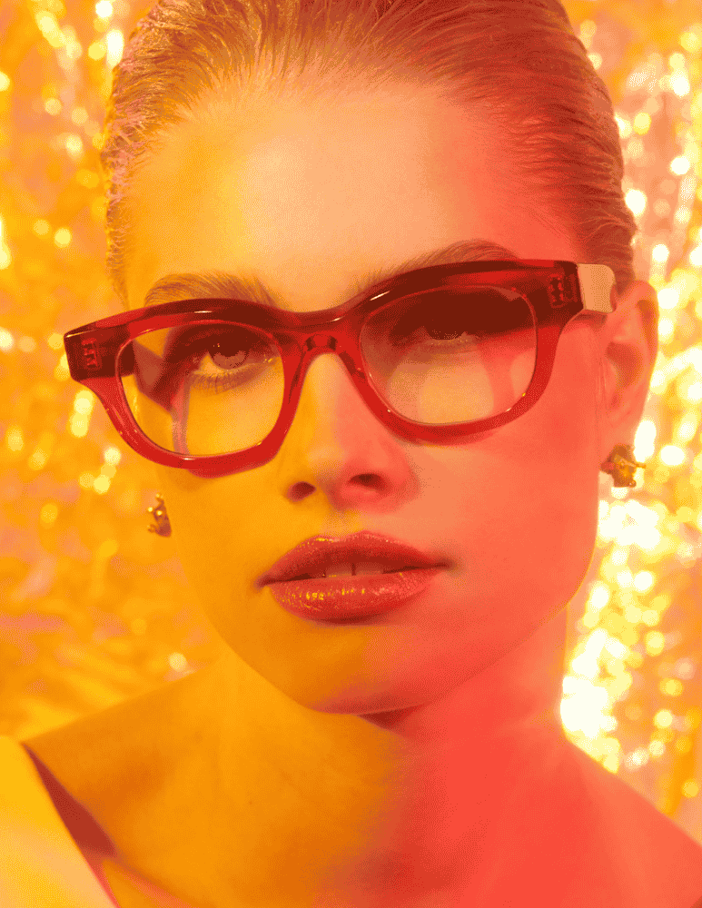 A close up of a woman wearing glasses and earrings.