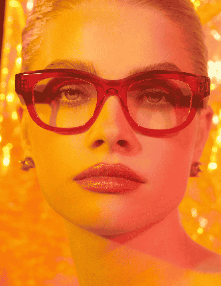 A close up of a woman wearing glasses and earrings.