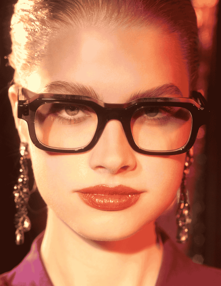 A close up of a woman wearing glasses and earrings