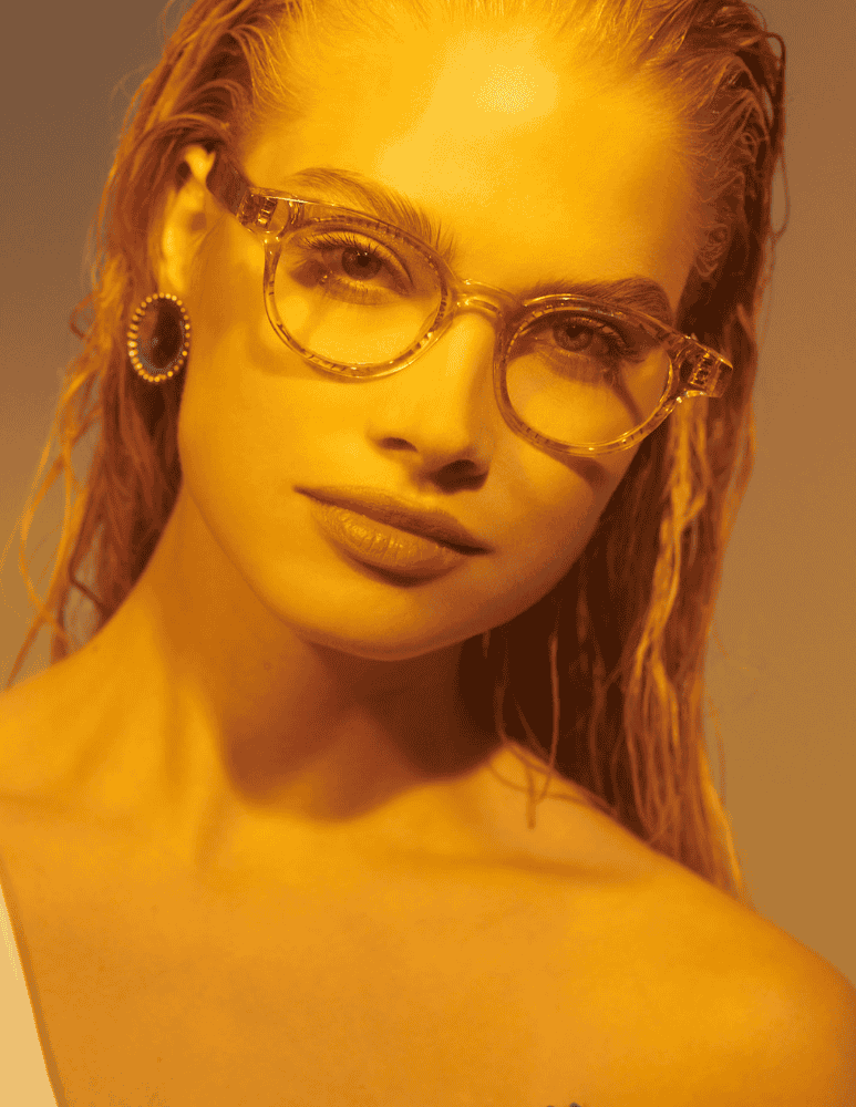A close up of a woman wearing glasses and earrings.