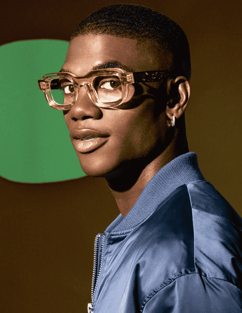 A man wearing glasses and a blue jacket is looking at the camera.