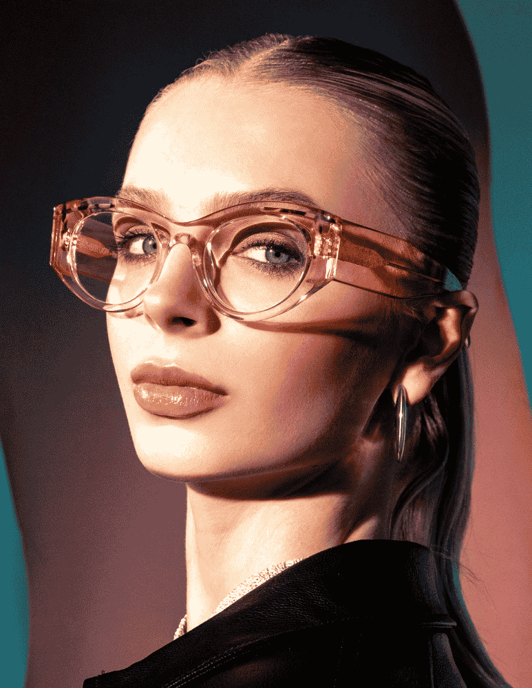 A woman wearing glasses and earrings is looking at the camera.