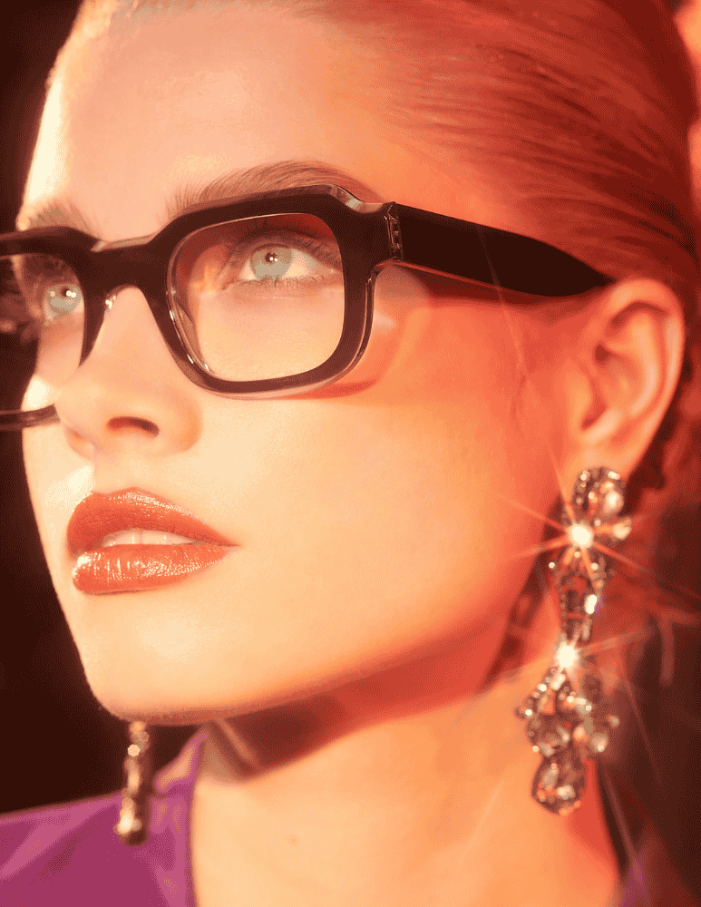 A close up of a woman wearing glasses and earrings