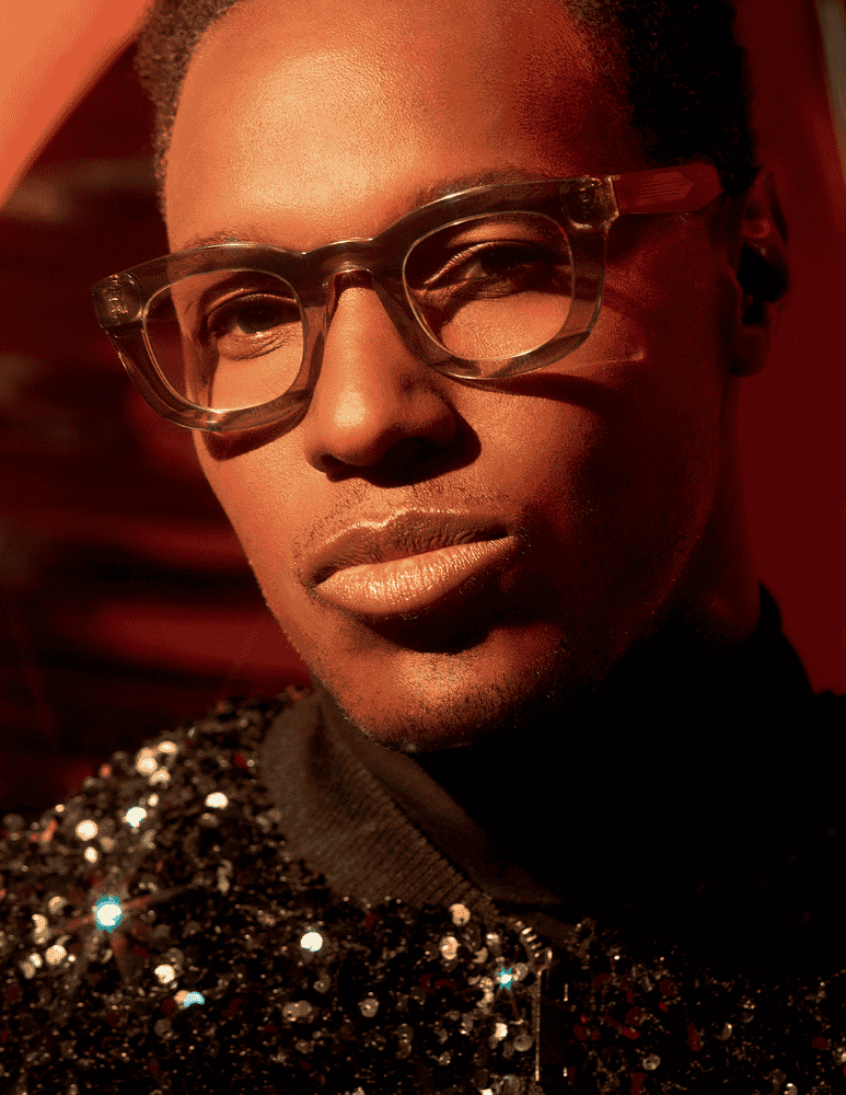 A close up of a man wearing glasses and a sequined jacket