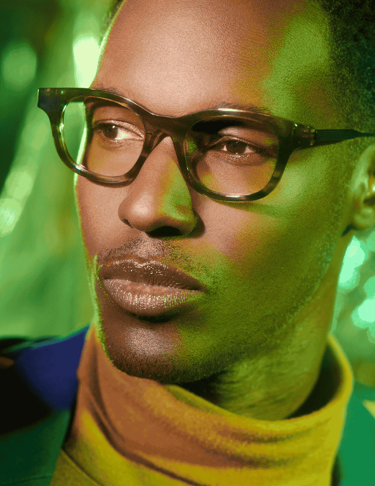 A close up of a man wearing glasses and a yellow turtleneck.