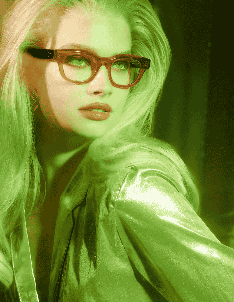 A woman wearing glasses and a green jacket is glowing in the dark.