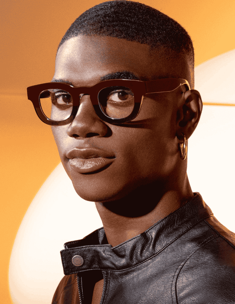 A close up of a man wearing glasses and a leather jacket