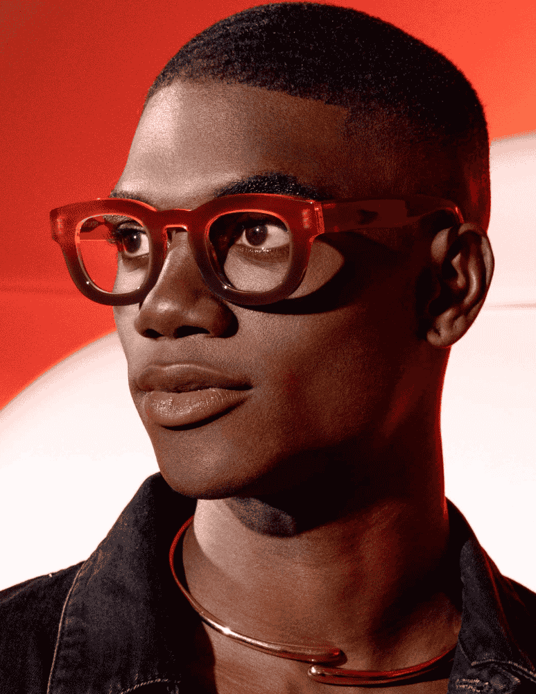 A close up of a man wearing glasses and a necklace.