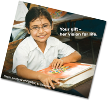 A girl with glasses sits at a desk with the words your gift her vision for life