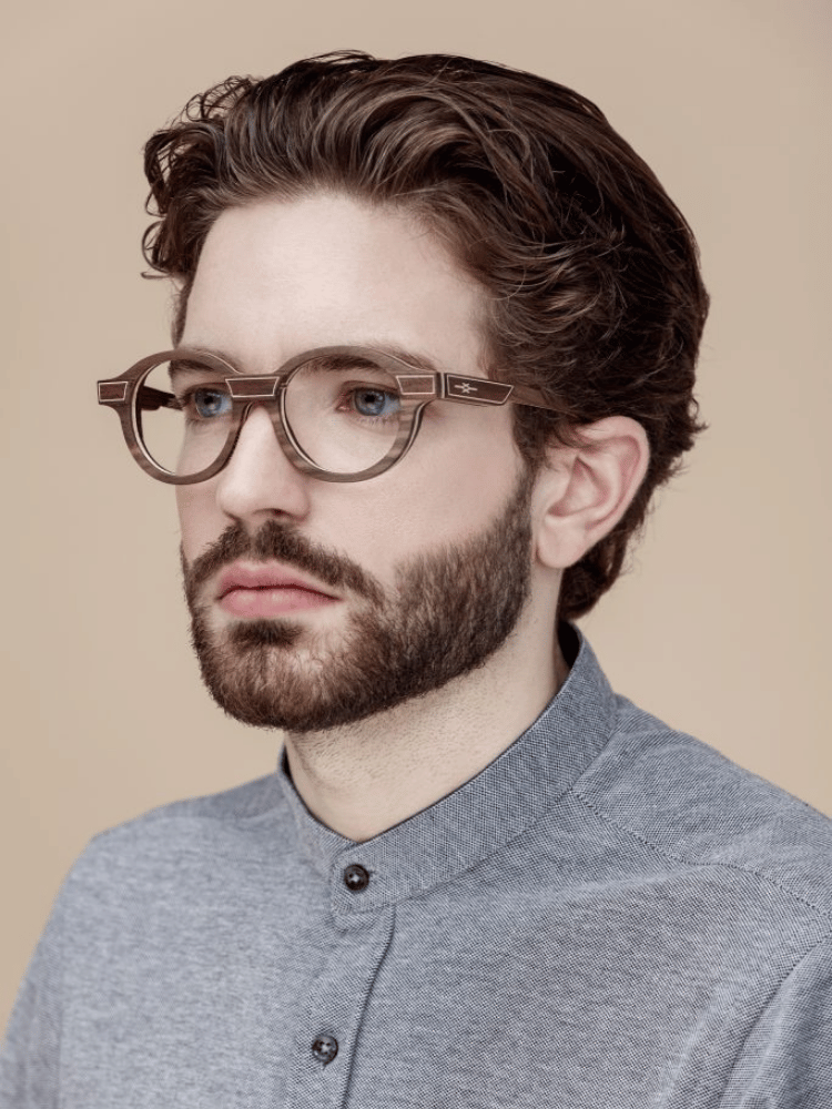 A man with a beard wearing glasses and a blue shirt