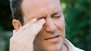 A man is rubbing his eyes because he has a headache.