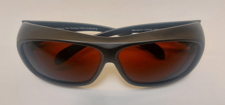 Black wraparound sunglasses with orange-tinted lenses on a white background