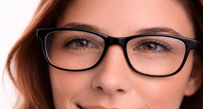 Woman wearing black eyeglasses, smiling, close-up.